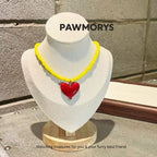 Lemon-yellow bead necklace with a glossy red heart pendant on a jewelry display